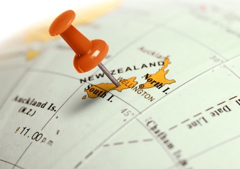 A close of the part of a globe map of the Earth, with a drawing pin stuck into New Zealand
