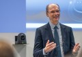 A smiling, bespectacled Peter Woodgate pictured speaking at an event, gesturing with his arms