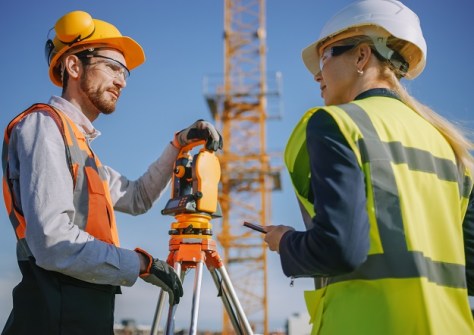 A man and a woman standing next to each other and with engineering surveying equipment