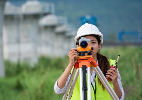 A surveyor looking through a surveying instrument