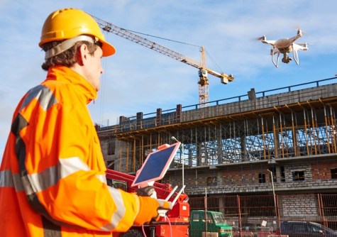 A man in safety gear on a construction site, holding a controller for a drone, of the kind used in the microcredentials skills courses.