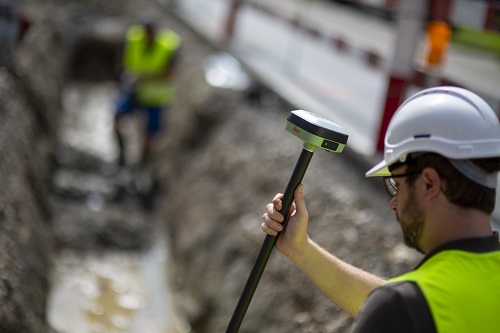 A surveyor using the Leica Geosystems GS05 GNSS smart antenna, attached to a pole that is being held at an angle.