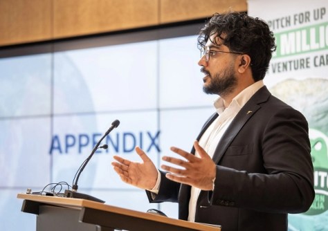 Shoaib Iqbal, CEO of Earth observation company, Esper Satellites, standing and speaking at a lectern.
