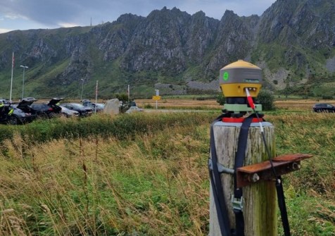 A FinPos precise positioning reference station in the foreground, with fields, a carpark and mountains in the background. The picture was taken during GNSS interference testing.