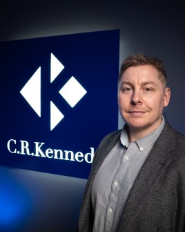 Philip Byrne, Product Manager, C.R. Kennedy, standing in front of the company logo on a wall