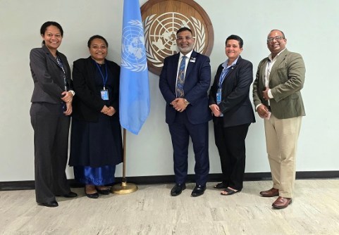 Zaffar Sadiq Mohamed-Ghouse and four other people, standing next to a UN flag