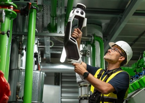 A man holding a NavVis MLX scanner, conducting reality capture inside a factory