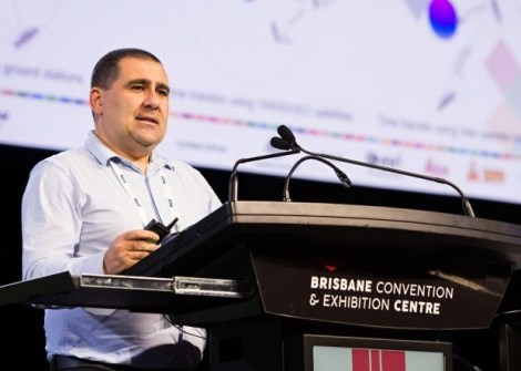 Eldar Rubinov standing behind a lectern, giving a presentation.