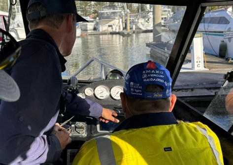 Two people at the controls of a boat, during a hydrographic surveyors course