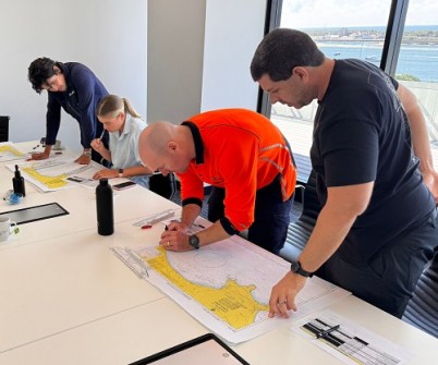 Four people standing and sitting at a desk, during a hydrographic surveyors course