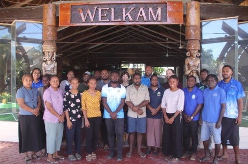 A group of people standing under a welcome sign, during training on GIS tools and remote sensing