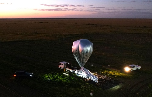 An aerial view of a large Stratoship balloon being filled with helium at dawn