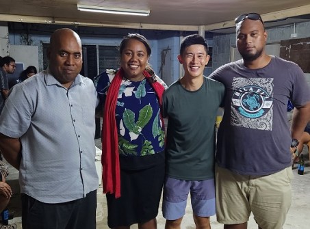 Four people standing shoulder to shoulder in a room