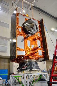 The Sentinel-6B spacecraft, with parts covered in gold foil, standing upon a trolley inside a clean room