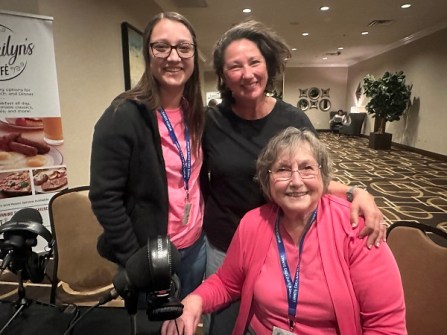 Two women standing and one woman sitting, together in a corridor, at the Women Surveyors Summit