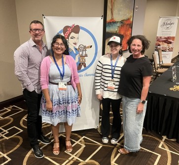 One man and three women standing together indoors at the Women Surveyors Summit