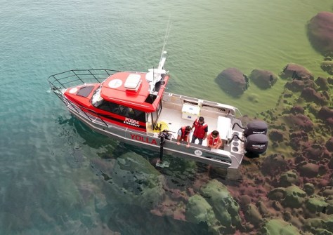 An overhead view of small boat belonging to Deakin University, with several people aboard conducting sonar mapping.