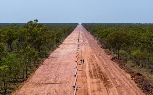 A wide swath of land, about 50 metres wide, cleared for a gas pipeline, disappearing into the distance through remote Australia