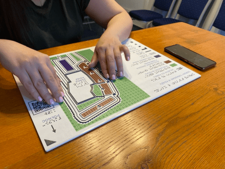 A tactile map on a desk, with a person's two hands touching it to read it.