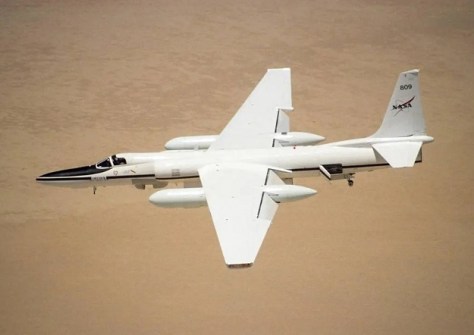 A photo of NASA's slender ER-2 aircraft flying over a desert. The ER-2 has carried the AVIRIS payload.