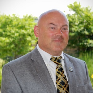 A head-and-shoulders image of a man wearing a suit and tie