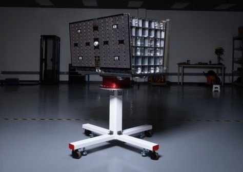 A small satellite from the company Xona, sitting on a stand inside a clean room