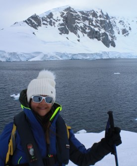 Ari Comben, pictured standing in an icy environment in protective gear, pivoted from marine science to using GIS for preparedness for and recovery from disasters