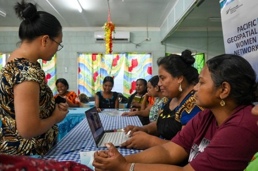 Kiribati women sitting at a table with a laptop computer
