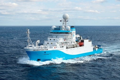 A view of the blue-and-white, multi-storey ship, the RV Investigator, at sea