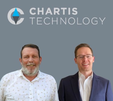 Two men standing side by side in front of a grey wall on which is displayed the logo for Chartis Technology
