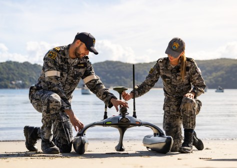 Two sailors with a small sonar boat on a beach during geospatial intelligence training