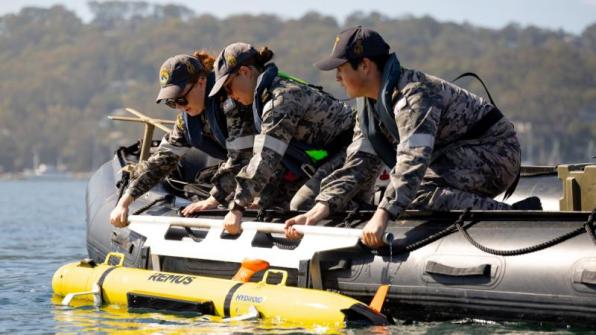 Three sailors in a dinghy during a geospatial intelligence exercise