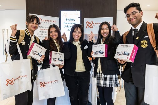 Smiling students and their teacher, holding their drone prizes