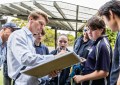 A surveyor speaking with school students