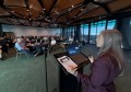 A woman standing at a lectern with the audience in front of her, speaking about AI