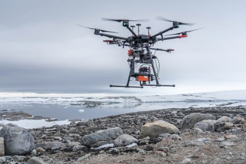 A drone hovering just above a rocky shoreline in Antarctica