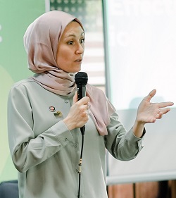 A woman holding a microphone and speaking to an audience