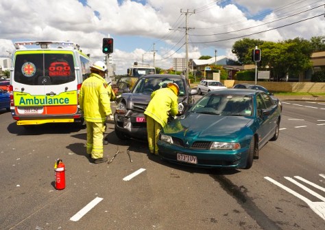 A photo of two cars involved in a road crash, with an ambulance parked alongside and emergency workers present