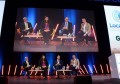 Four people on stage during a discussion panel at the Locate conference