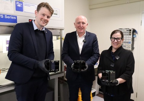 Three people, each holding in front of them a Binar CubeSat