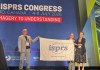 Three people holding a banner on a stage