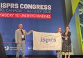 Three people holding a banner on a stage
