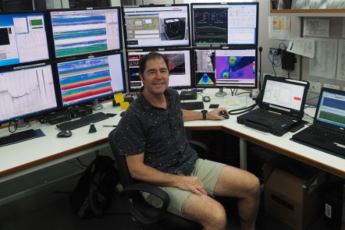 A man sitting a desk full of computer screens, during seabed mapping operations