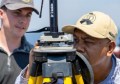 A man peering closely at a surveying instrument