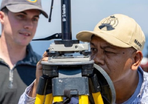 A man peering closely at a surveying instrument