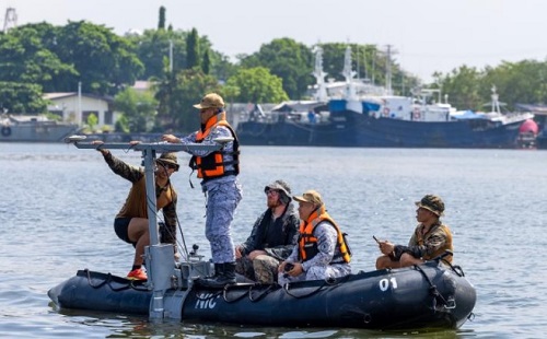 Royal Australian Navy and Philippine Navy personnel in a small boat, conducting hydrographic surveying tasks
