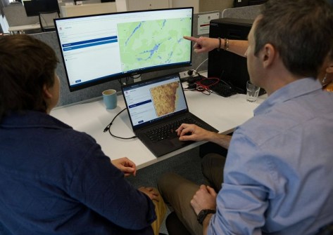 Three people at a desk, looking at the Bionet Atlas on a computer screen