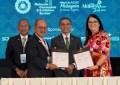 Four people standing together, holding documents signed to signify a partnership agreement between ASEAN FLAG and Surveyors Australia