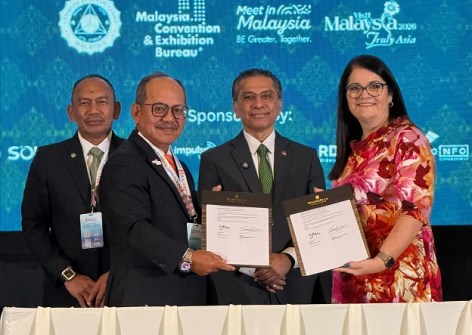 Four people standing together, holding documents signed to signify a partnership agreement between ASEAN FLAG and Surveyors Australia