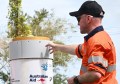 A man in orange safety gear and cap, standing next to a CORS, pointing at it